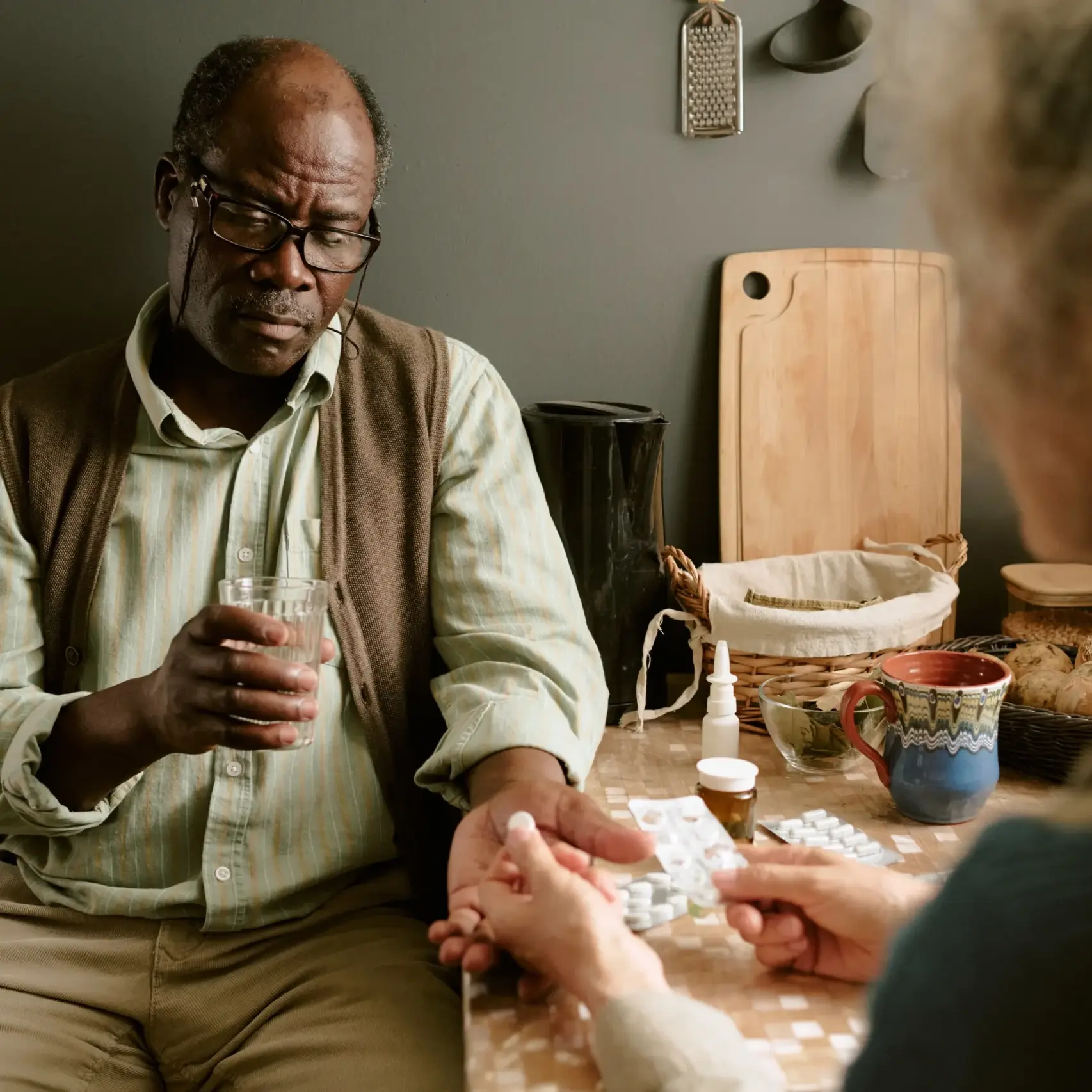 Elderly man with Alzheimer’s receiving medication support from caregiver at home.