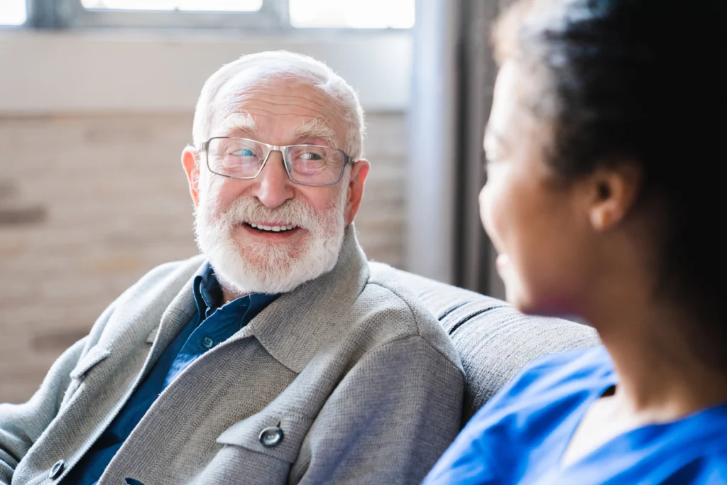 Senior man with Alzheimer’s smiling while communicating with caregiver.