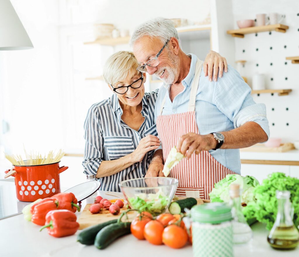 Senior couple preparing a healthy meal with fresh vegetables in the kitchen to support balanced nutrition and healthy aging.