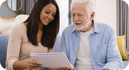 Caregiver reviewing documents with an elderly man at home.